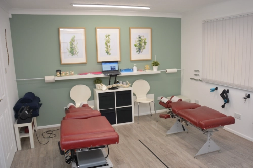 Inside the clinic: two treatment tables, shelving and framed prints in a calm treatment room
